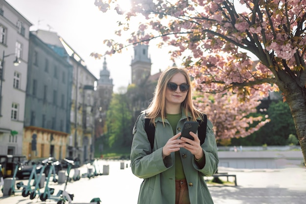 Stylish clothes blond girl tourist travels looking for directions on smartphone while traveling thro