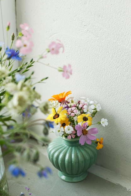 Stylish colorful wildflowers bouquet on tile shelf on rustic wall background Beautiful summer flowers in vase gathered from garden floral arrangement in modern room in home