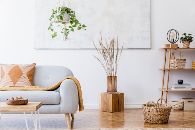 Stylish composition of creative cozy spacious apartment interior with grey sofa, coffee table, plants, carpet, chair, pillows, plaid and accessories.