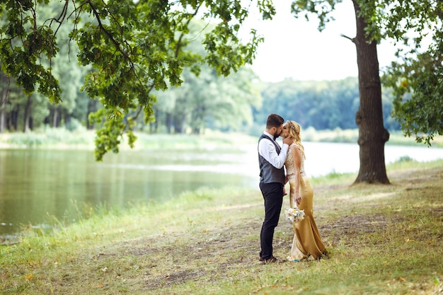 Stylish couple of happy newlyweds posing in the park on their wedding day Perfect couple bride groom