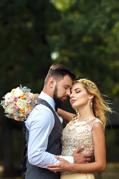 Stylish couple of happy newlyweds posing in the park on their wedding day Perfect couple