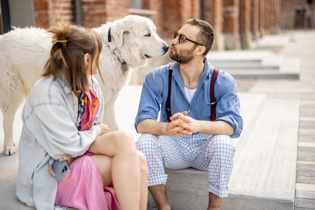 Stylish couple have fun and sit with their dog on a street