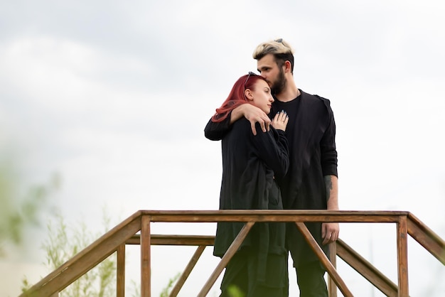 Stylish couple in love in black clothes are walking in the park and hugging Lovely hipster couple enjoying time together Youth love and lifestyle concept