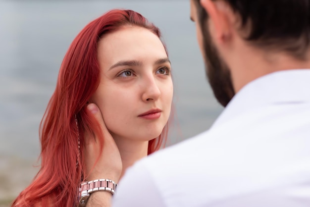 Stylish couple in love walks by the river Cute hipsters look into each other39s eyes on the background of water Closeup of a girl Youth love and lifestyle concept