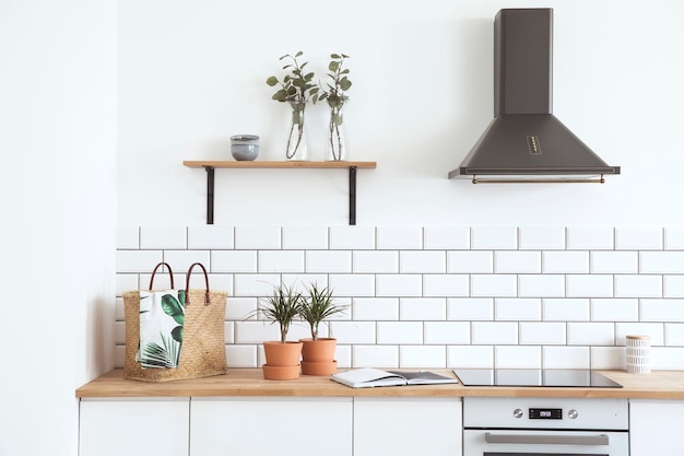 Stylish details of creative kitchen interior in scandinavian apartment with basket tiny plants and other accessoires White creative wall wooden furniture