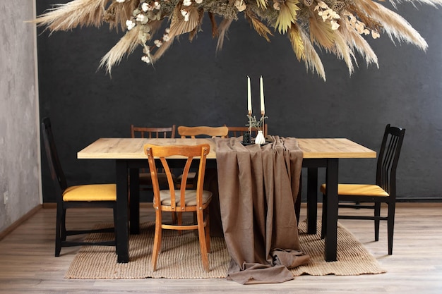 Stylish dinning room with wooden table and chairs and composition dry decoration plant on wall