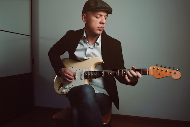 Stylish elegant man playing electric guitar making music indoors