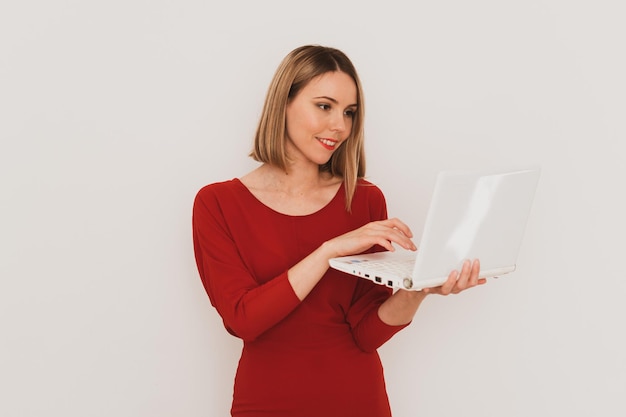 Stylish european woman in red dress using laptop for communication isolated on white background