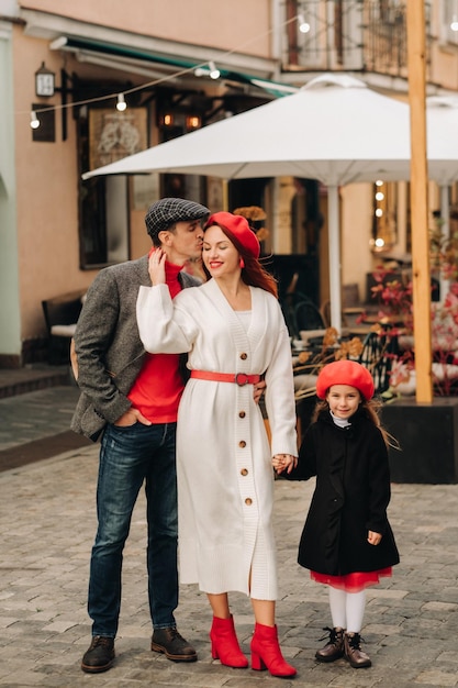 A stylish family of three strolls through the autumn city posing for a photographer Dad mom and daughter in the autumn city