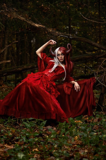 Stylish and fashionable model girl in the image of maleficent posing among mystic forest fairytale