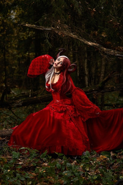 Stylish and fashionable model girl in the image of maleficent posing among mystic forest fairytale