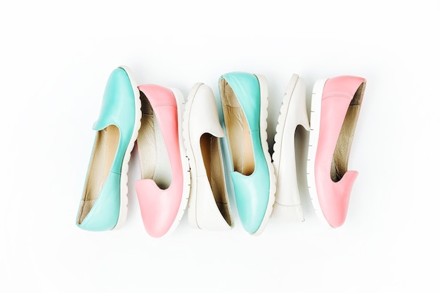 Stylish female shoes in pastel colors on white background, top view