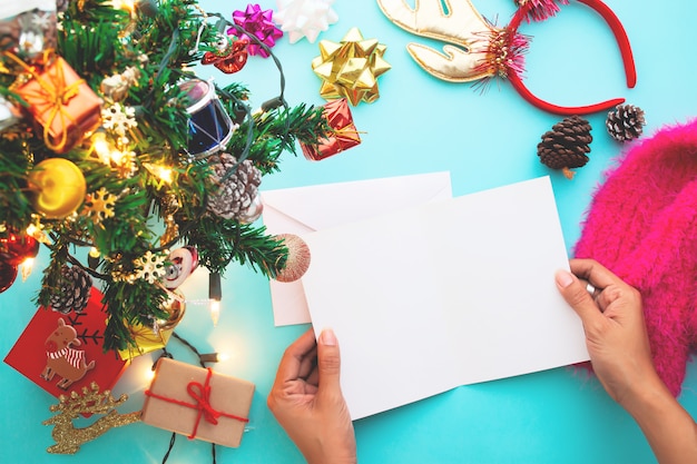 Stylish flat lay Christmas concept, woman holding blank card.