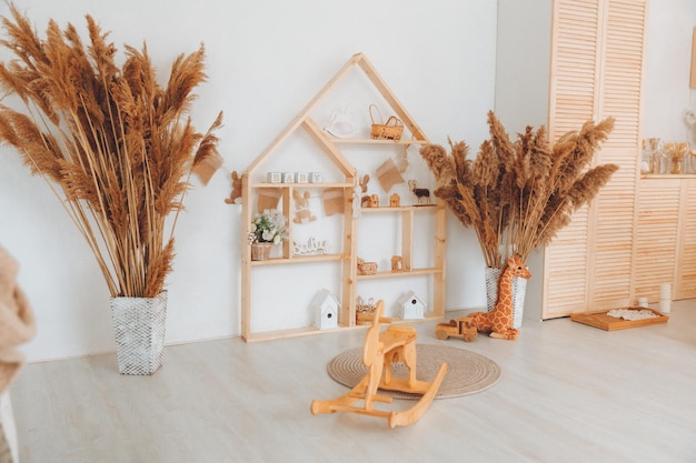 Stylish furniture in a bright spacious children's room with a wooden rocking horse white children's room in Scandinavian style