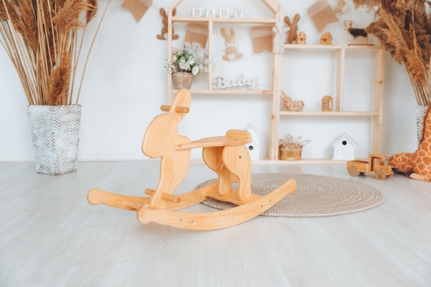 Stylish furniture in a bright spacious children's room with a wooden rocking horse white children's room in Scandinavian style