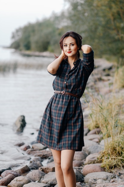 Stylish girl in a dress standing on the beach and straightening her hair