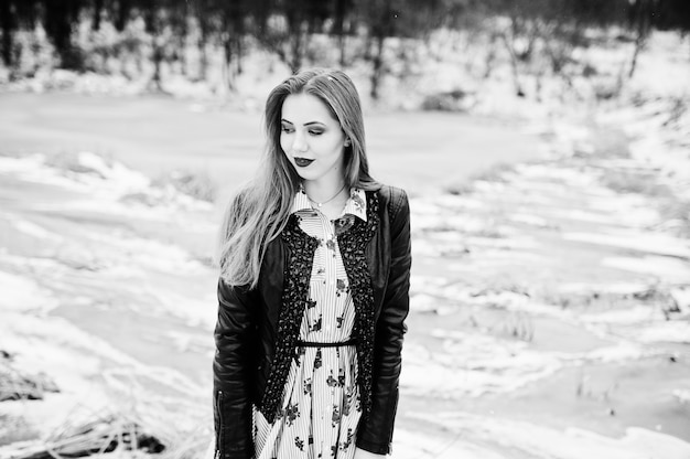 Stylish girl in leather jacket at winter day against frozen lake.