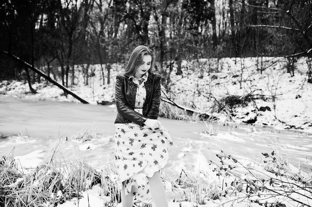 Stylish girl in leather jacket at winter day against frozen lake.