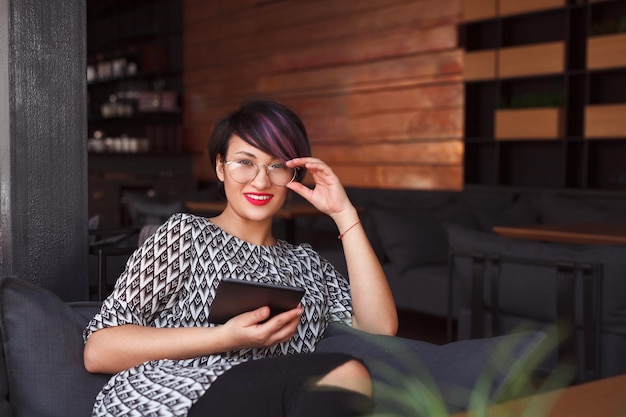 Stylish girl with tablet in cafe