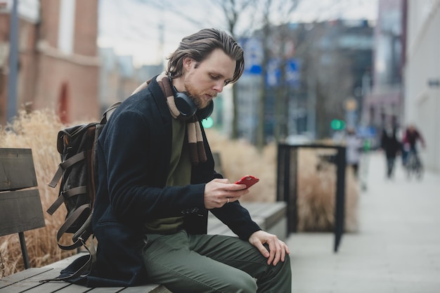 Stylish guy in scarf and coat hold mobile phone in a hand at street of Wroclaw Poland