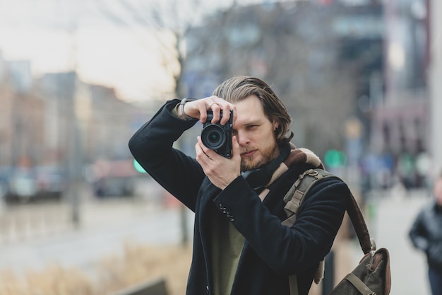 Stylish guy in scarf and coat hold a photo camera at street of Wroclaw Poland