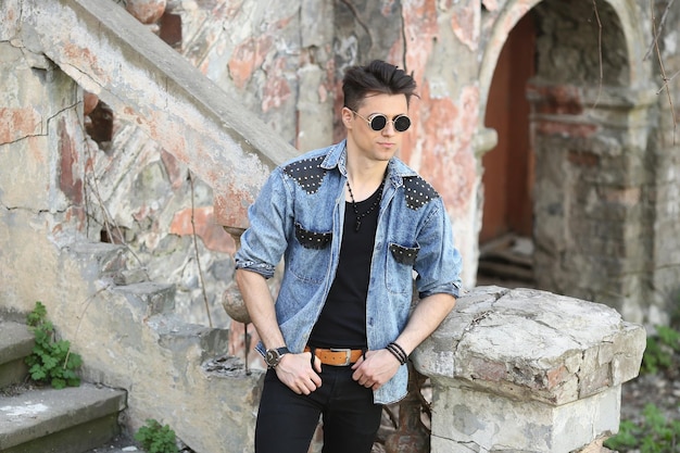 Stylish guy standing street in a denim jacket against men's looks