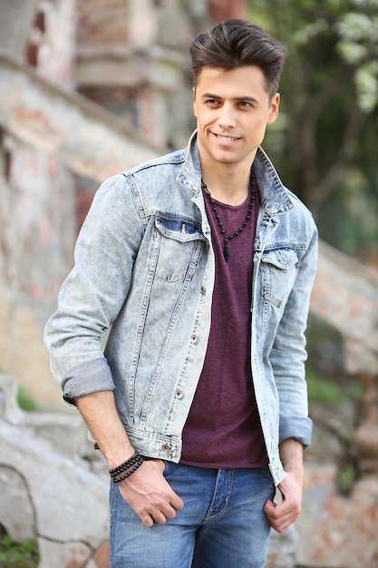 Stylish guy standing street in a denim jacket against men's looks