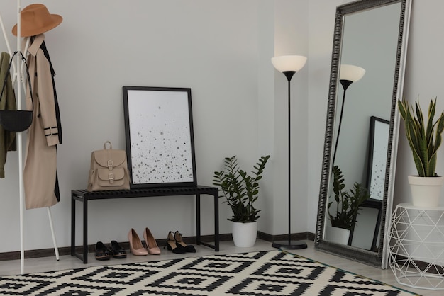 Stylish hallway room interior with bench shoes clothes rack and floor mirror