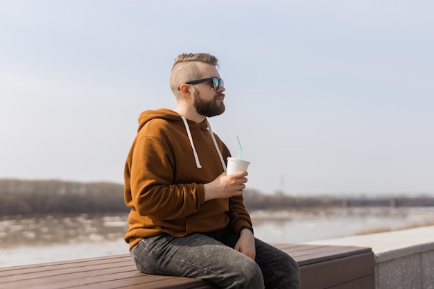 Stylish handsome hipster man holding drinks cocktail spring time copy space