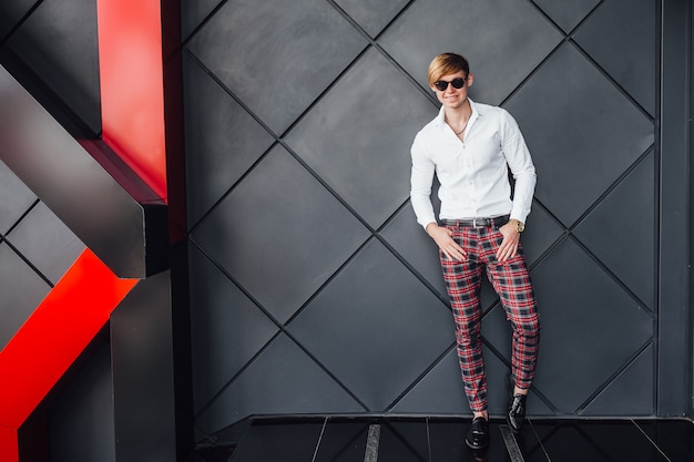 Stylish handsome man standing near modern black building.