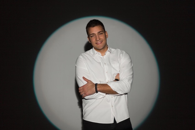 Stylish handsome professional business man with a smile in a white Tshirt on a dark background