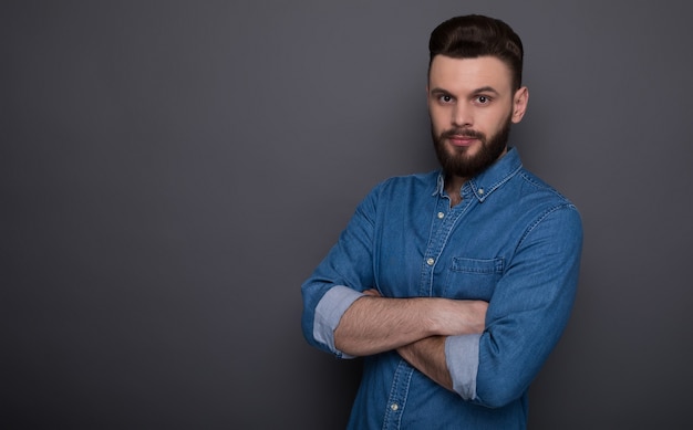 Stylish handsome trendy fashion bearded man in denim wear is posing 