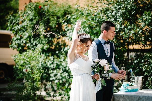 Stylish happy bride pours out champagne over the head. Wedding ceremony.