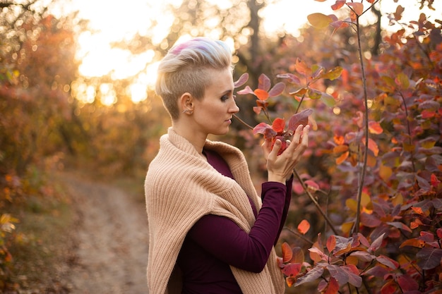 Stylish hipster woman smiling and playing with autumn leaves in park Autumn woman fall