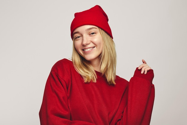 Stylish hipster woman wearing stylish red hat and sweatshirt smiling at