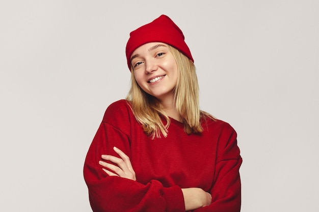 Stylish hipster woman wearing stylish red hat and sweatshirt smiling at