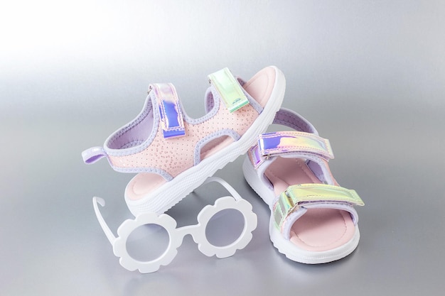 Stylish holographic sandals for kids on grey background Shiny fashion summer shoes