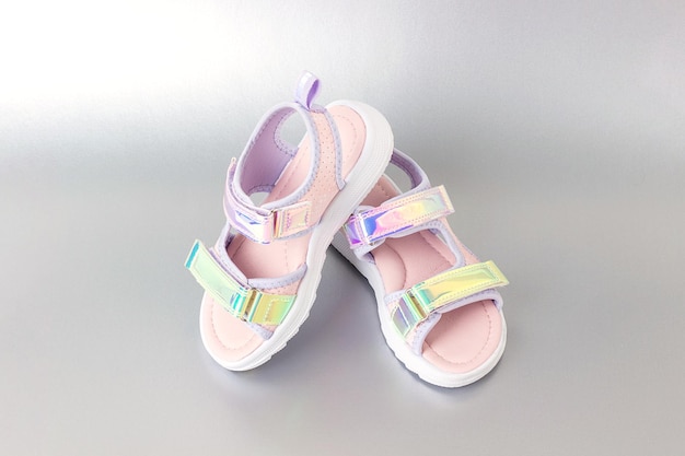 Stylish holographic sandals for kids on grey background Shiny fashion summer shoes