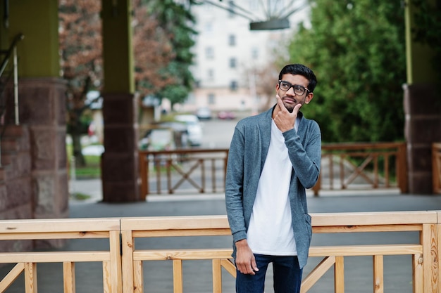 Stylish indian man at glasses wear casual posed outdoor and thinking