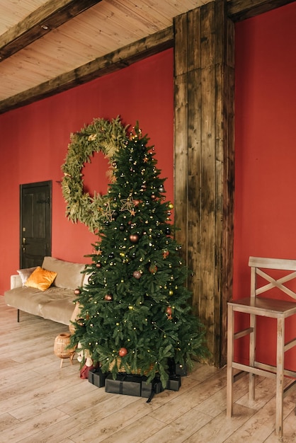 Stylish interior of the living room with a Christmas tree on a red background