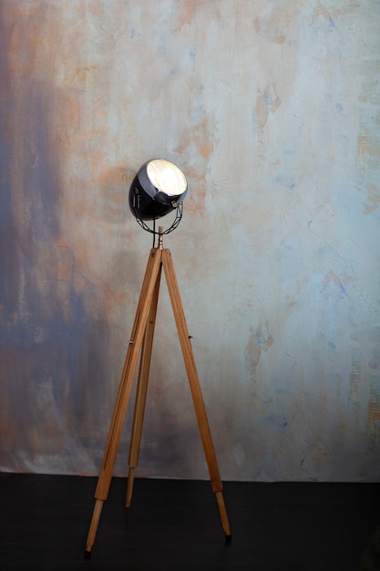 Photo stylish lamp on tripod in room.