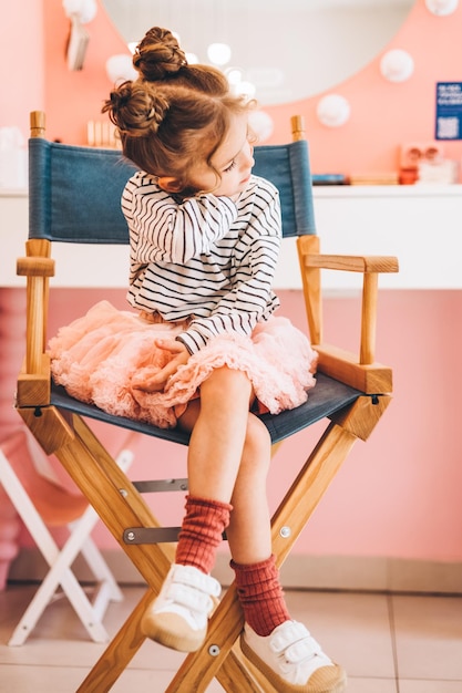 Stylish little girl in a beauty salon for children where she made a beautiful hairstyle Beauty and kid fashion with healthy hair