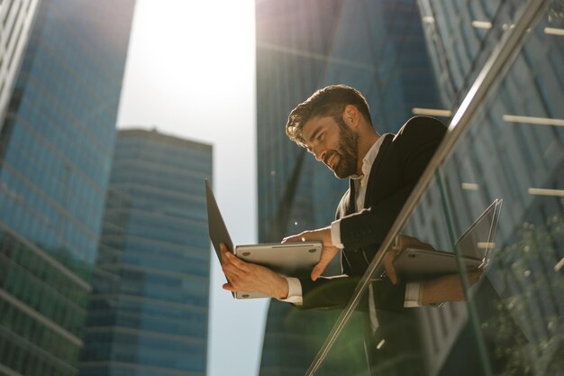 Stylish male manager working on laptop standig on office terrace high quality photo