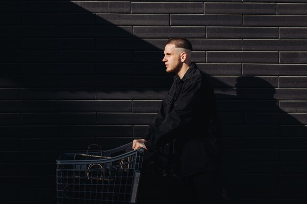 Stylish man in black with shopping bags  in a trolley on Black Friday