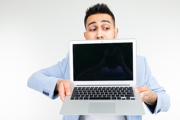 Stylish man in a blue jacket shows a laptop display with a blank template for inserting a site on a white studio background