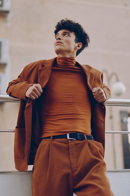 Stylish man in brown outfit posing confidently outdoors