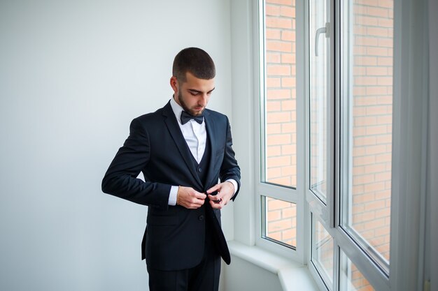 Stylish man businessman buttoning a button on a black jacket