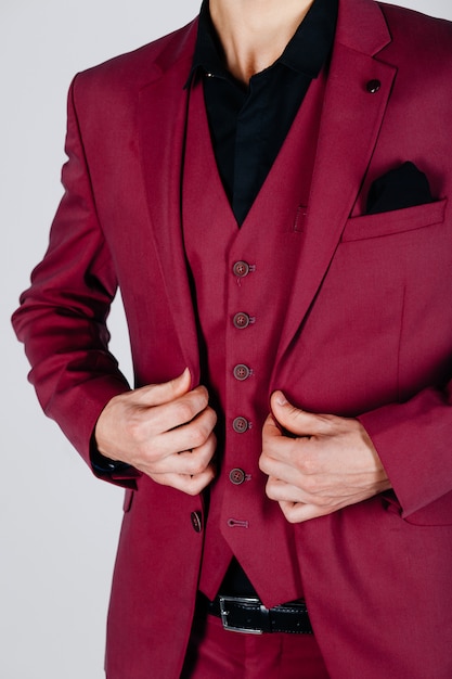 Stylish man in a crimson jacket on a light background