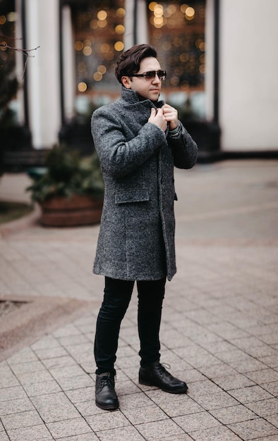 stylish man in a gray coat and sunglasses walking in the city.