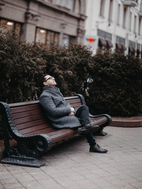 stylish man in a gray coat and sunglasses walking in the city.